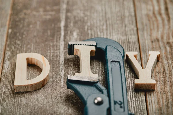 Close up of wooden diy sign and part of pipe wrench tool on wooden background — Stock Photo