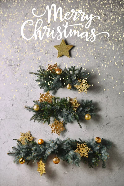 Albero di Natale fatto a mano e stella appesa al muro grigio con scritte 