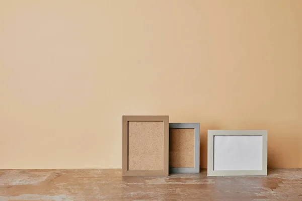 Photo frames on table on beige background — Stock Photo