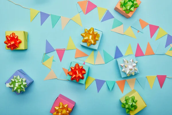 Vista superior de regalos de colofrul y banderines festivos sobre fondo azul - foto de stock