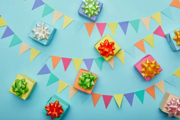 Vue du dessus des cadeaux et du bruant coloré festif sur fond bleu — Photo de stock