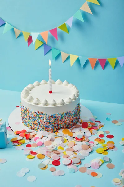 Tasty cake with sugar sprinkles and confetti on blue background with colorful bunting — Stock Photo