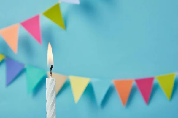 Candle on blue background with bunting — Stock Photo