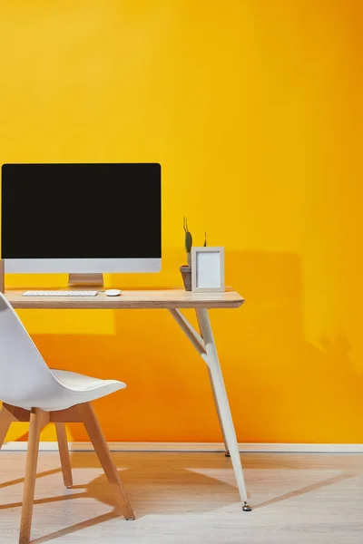 Lieu de travail avec ordinateur, cadre photo et cactus à la table en bois — Photo de stock