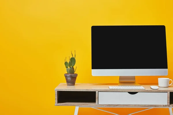 Kaktus im Blumentopf, weiße Tasse und Computer am Arbeitsplatz auf gelb — Stockfoto