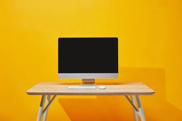 Компьютер с клавиатурой и мышью за деревянным столом на желтом — стоковое фото