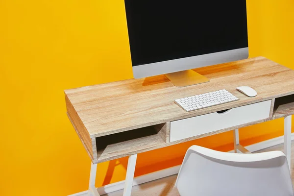 Close-up de local de trabalho com computador e mesa de madeira perto da parede amarela — Fotografia de Stock