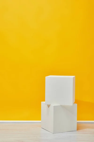 Dois cubos de gesso dispostos verticalmente perto da parede amarela — Fotografia de Stock