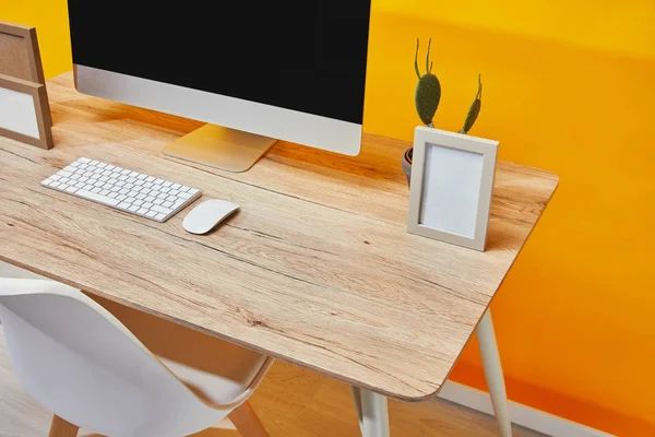 Computer, empty photo frames and cactus in flowerpot at wooden table — Stock Photo