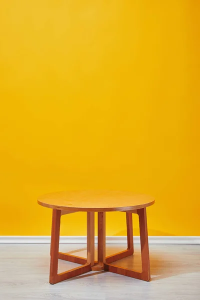 Little wooden coffee table with yellow wall at background — Stock Photo