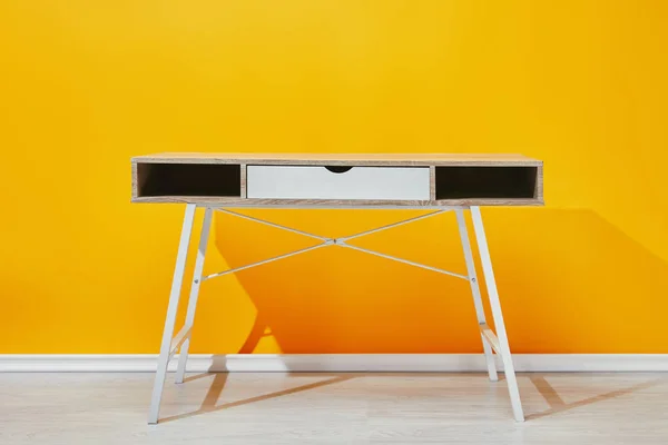Table en bois près du mur jaune vif — Photo de stock