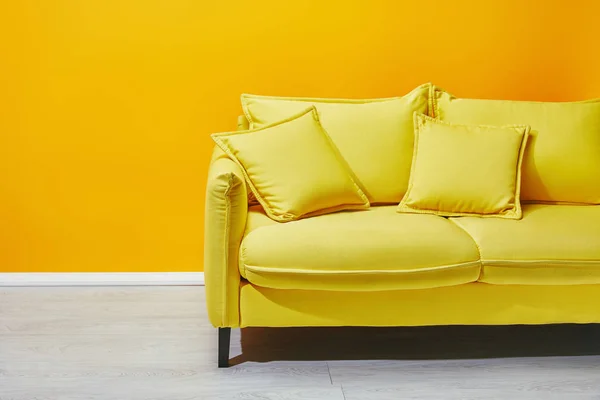 Sofa with pillows with yellow wall at background — Stock Photo