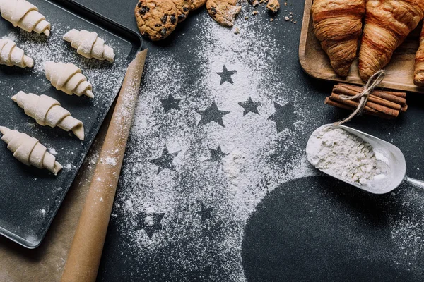 View from above of tray with dough for croissants on surface covered by flour with symbols of stars — Stock Photo