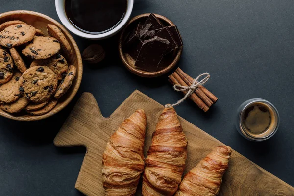 Vue de dessus de cannelle, café, croissants, chocolat et biscuits sur table noire — Photo de stock