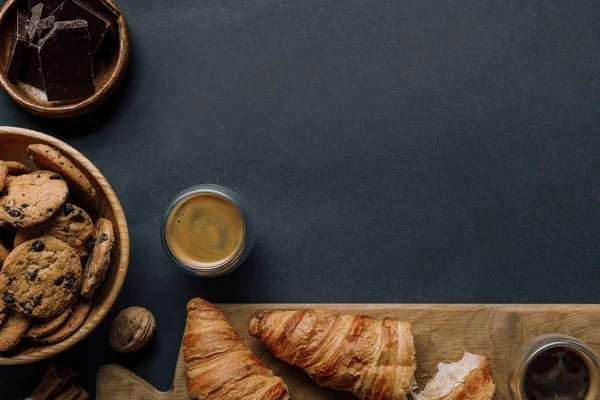 Vista superior de canela, café, croissants, chocolate e biscoitos na mesa preta — Fotografia de Stock