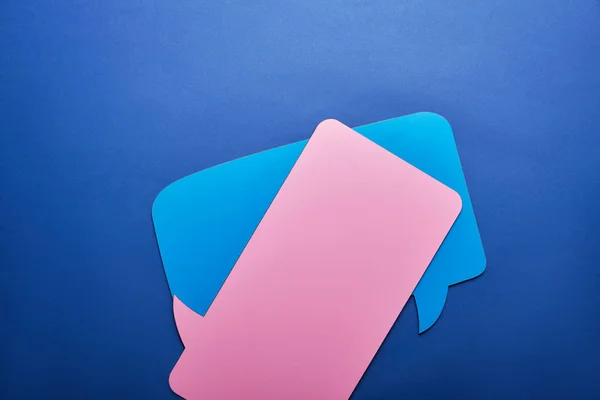 Elevated view of empty blue and pink speech bubbles on blue background — Stock Photo