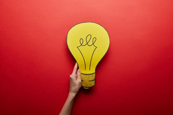 Vue du dessus de l'ampoule jaune en papier symbole idée sur fond rouge — Photo de stock