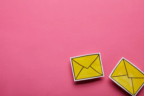 Vista superior de dos iconos de mensaje amarillo sobre fondo rosa - foto de stock