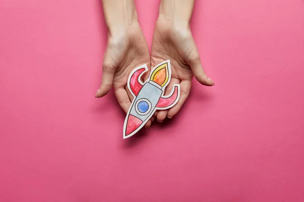 Top view of hands holding rocket on pink background — Stock Photo