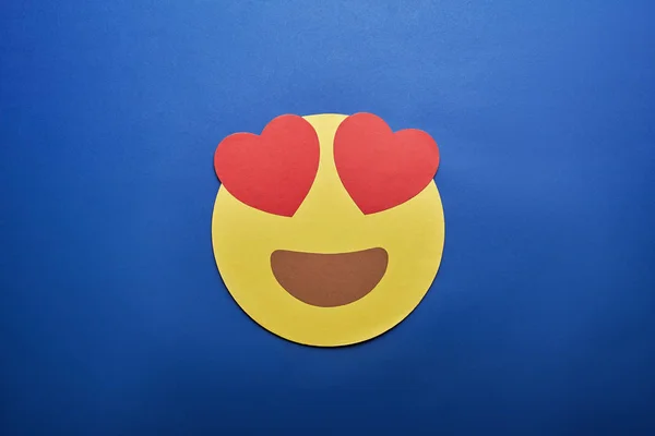 Vue du dessus de dans l'amour emoji sur fond bleu — Photo de stock