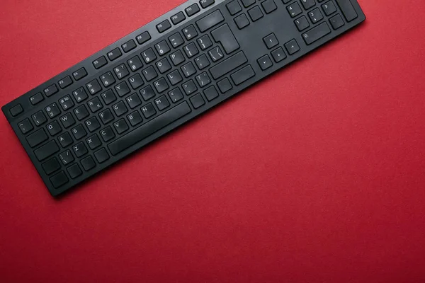 Вид зверху чорної комп'ютерної клавіатури на червоному тлі з простором для копіювання — стокове фото