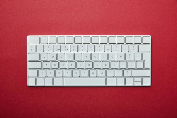 Vista superior del teclado del ordenador sobre fondo rojo - foto de stock