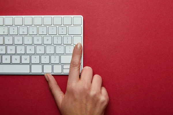 Vue recadrée de la femme appuyant sur le bouton sur le clavier de l'ordinateur sur fond rouge — Photo de stock