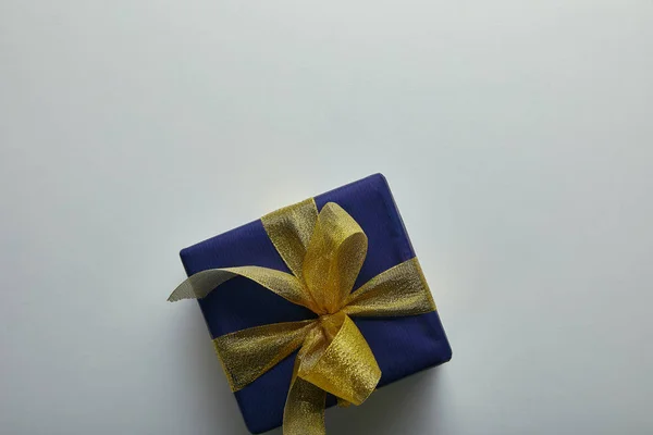 Vista superior del regalo envuelto en papel de regalo azul con cinta amarilla sobre fondo gris - foto de stock