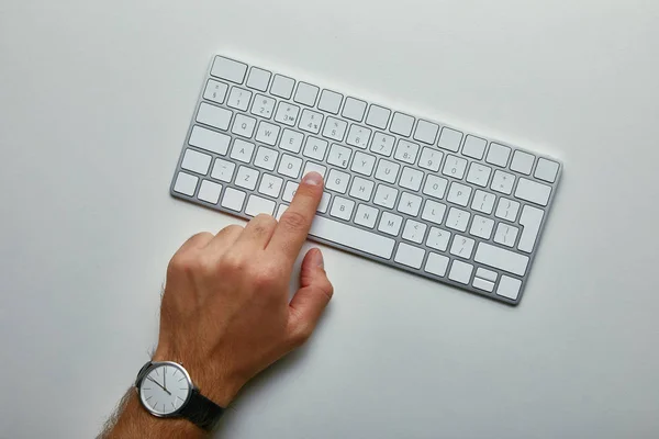 Vista ritagliata dell'uomo che preme il pulsante sulla tastiera del computer su sfondo grigio — Foto stock