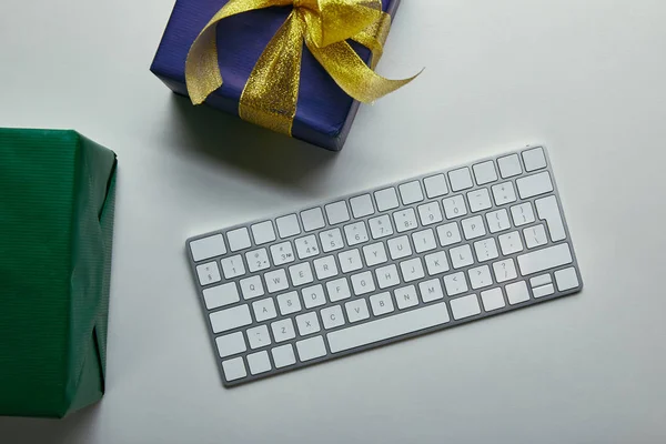 Обрізаний вигляд подарунків біля комп'ютерної клавіатури на сірому фоні — стокове фото
