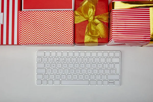 Visão superior de presentes coloridos perto do teclado do computador branco no fundo branco — Fotografia de Stock