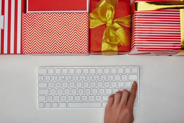Top view of woman pushing button on computer keyboard near presents on white background — Stock Photo