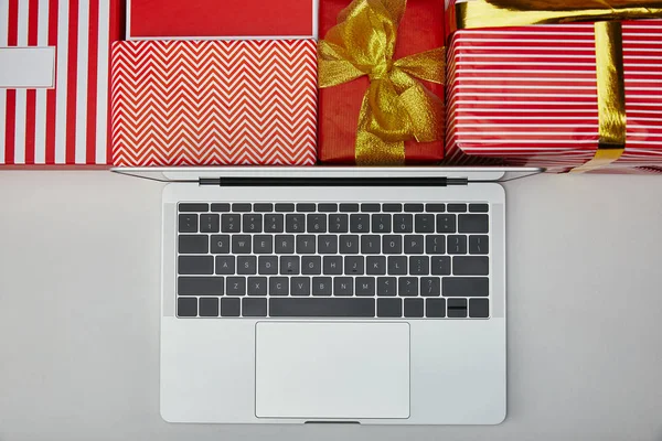 Top view of laptop near wrapped colourful gifts — Stock Photo