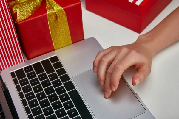 Vue recadrée de la femme à l'aide de pavé tactile sur ordinateur portable près de cadeaux enveloppés — Photo de stock