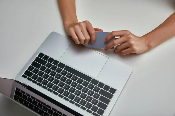 Top view of woman holding credit card near laptop on white background — Stock Photo