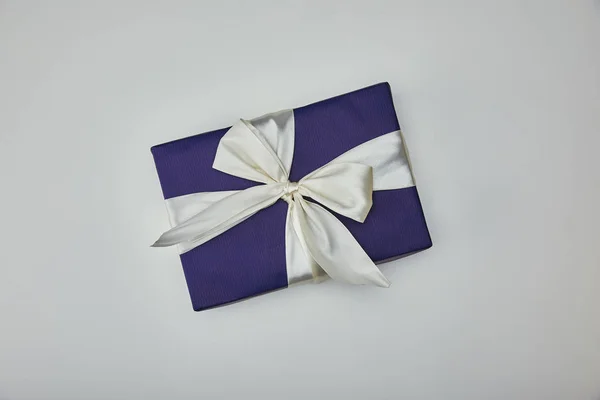 Top view of wrapped present with white ribbon isolated on grey background — Stock Photo