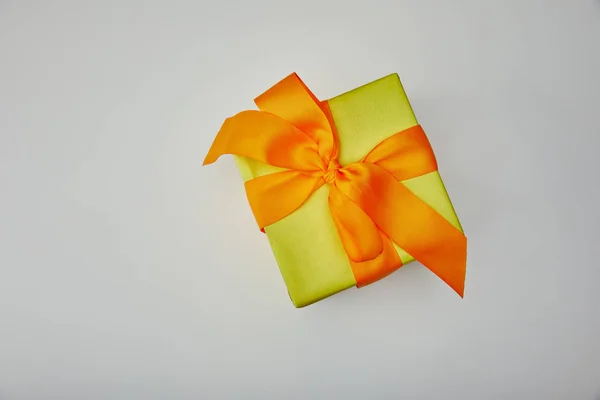 Draufsicht auf verpacktes Geschenk mit orangefarbener Schleife isoliert auf grauem Hintergrund — Stockfoto