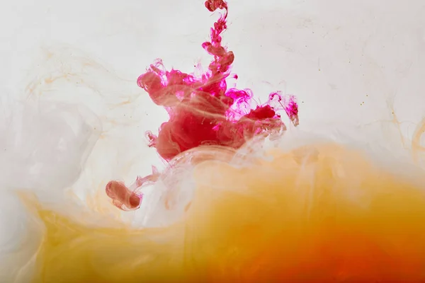 Abstracto de color rosa y naranja remolinos de pintura sobre fondo blanco - foto de stock