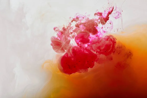 Pink and orange swirls of paint on white background — Stock Photo