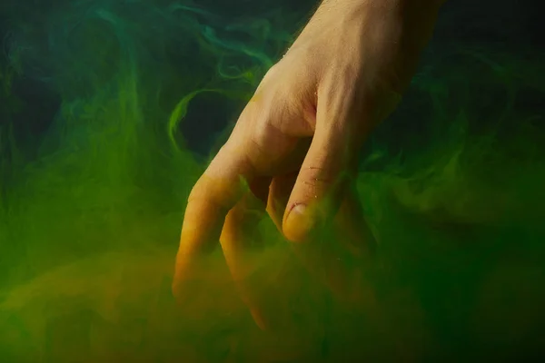 Cropped view of hand in water with green paint swirls — Stock Photo