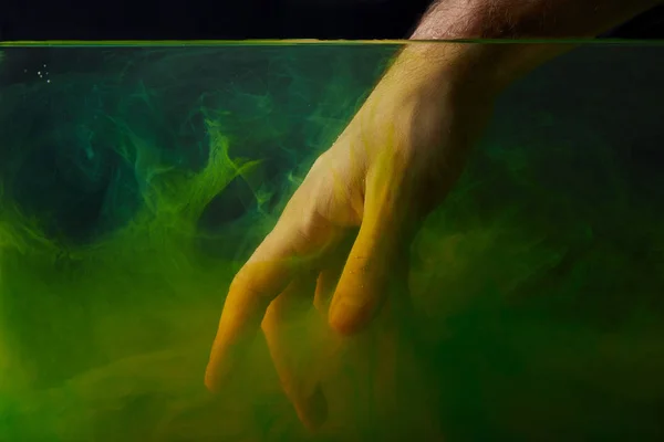 Main dans l'eau avec des tourbillons fumés verts — Photo de stock