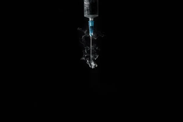 Syringe with smoke or paint swirls isolated on black — Stock Photo