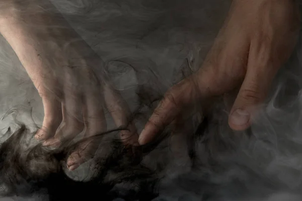 Vista cortada do casal tocando os dedos na água com tinta escura — Fotografia de Stock