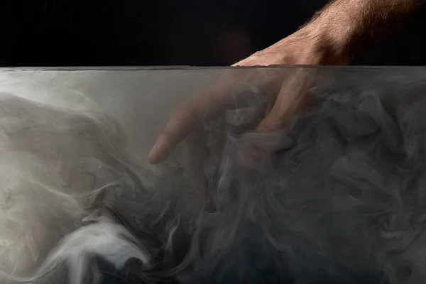 Cropped view of male hand in water with dark paint — Stock Photo