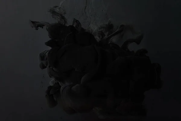 Брызги черной краски на темном фоне — стоковое фото