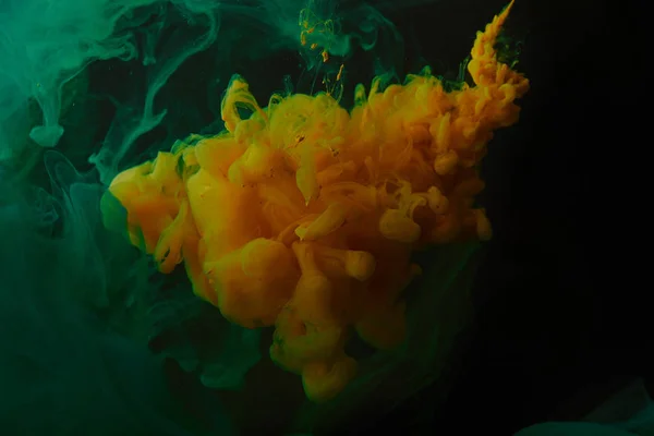 Fondo creativo con remolinos verdes y naranjas de pintura en agua - foto de stock