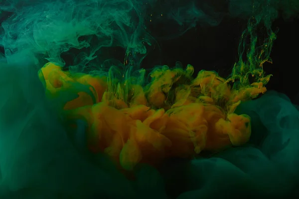 Абстрактный фон с зелеными и оранжевыми вихрями краски в воде — стоковое фото