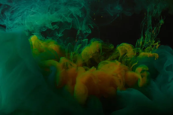 Fondo abstracto con mezcla de remolinos verdes y naranjas de pintura - foto de stock