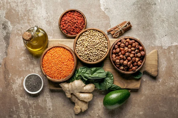 Vista superior de legumes, gengibre, sementes de chia e abacate em tábua de madeira com fundo rústico — Fotografia de Stock