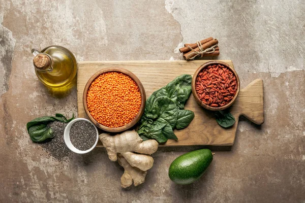 Vista dall'alto di lenticchie rosse, zenzero, semi di chia e avocado su tavola di legno con sfondo rustico — Foto stock